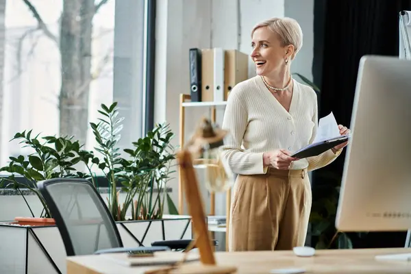 stock image A middle-aged businesswoman with short hair working diligently in a modern office setting in front of a computer.