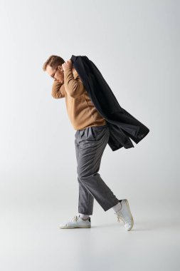 Kahverengi kazaklı, siyah ceketli şık bir adam..