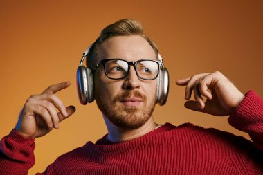 Stylish man with headphones pointing energetically to the side. clipart