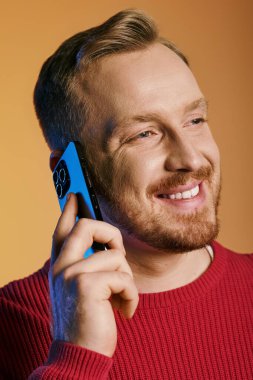 Kırmızı kazaklı şık adam cep telefonuyla konuşuyor..