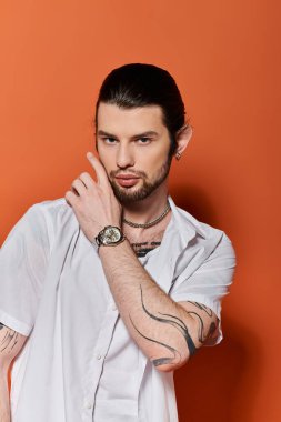 Tarz sahibi beyaz bir adam kendine güvenen bir duruşta kol dövmeleri yapıyor..