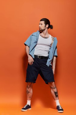 Atkuyruklu yakışıklı adam parlak turuncu arka planda güvenle duruyor..