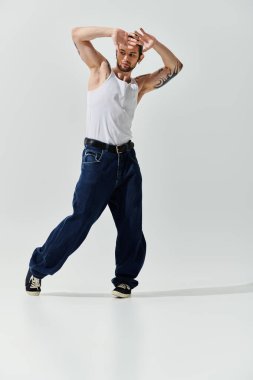 Beyaz gömlekli ve kot pantolonlu yakışıklı beyaz adam zarif bir şekilde dans ediyor..