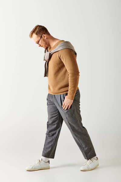 Стильный мужчина уверенно ходит в уютном свитере.