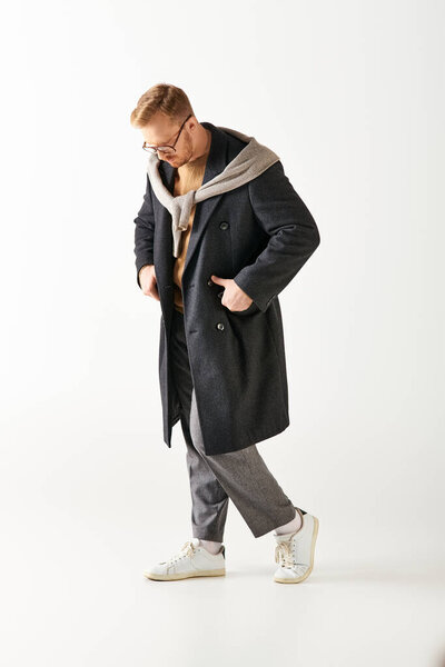 Стильный, загадочный человек уверенно шагает в черном пальто.