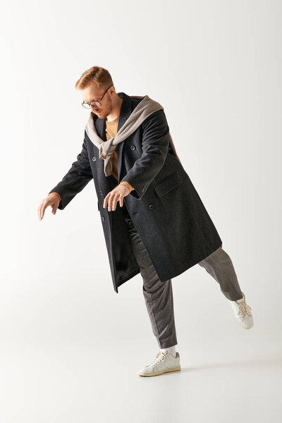 Красивый мужчина в стильной одежде активно танцует.