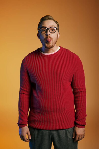 A charming man in a red sweater joyfully pulls a funny face.
