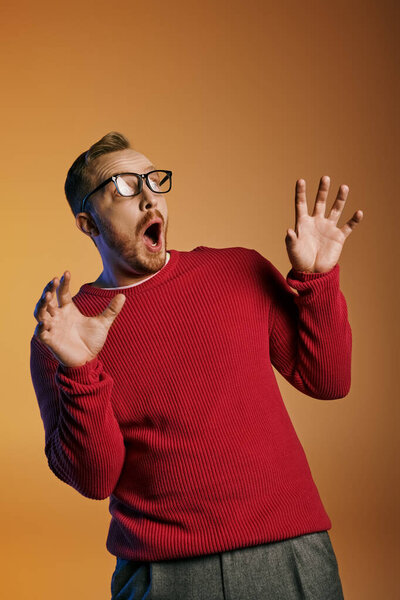 A stylish man in a red sweater contorts his face into an odd expression.