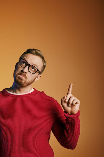 A stylish man in a red sweater pointing enthusiastically.