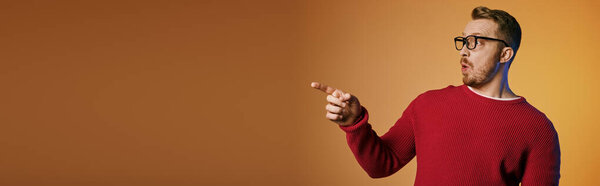 Handsome man in red sweater actively pointing at something.