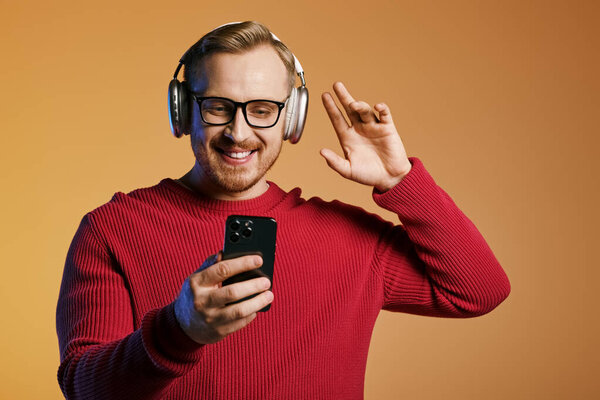 Стильный мужчина, наушники включены, телефон в руке, погружен в музыку.