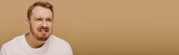 A man in a white shirt is making a face.