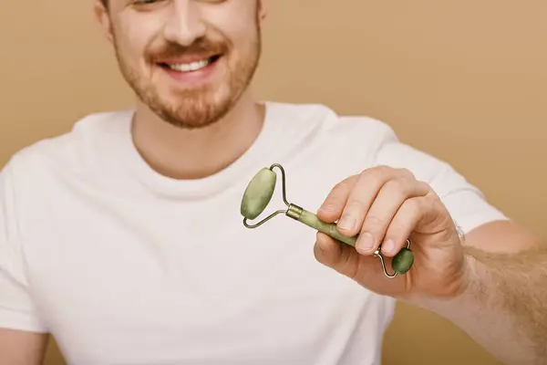 stock image A man in casual attire holding face roller.