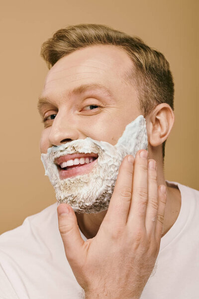 A man in casual attire carefully shaves his face.