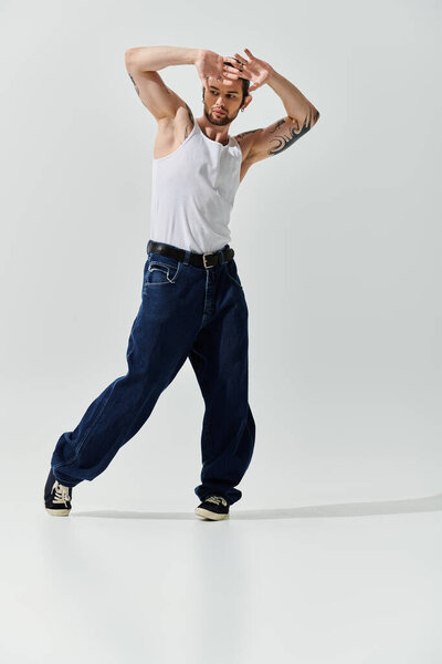 Красивый белый мужчина в белой рубашке и джинсах танцует изящно.