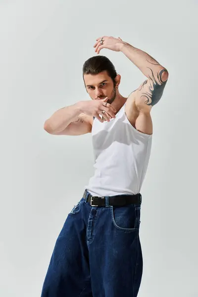 stock image A handsome Caucasian man in a white shirt and jeans poses confidently.