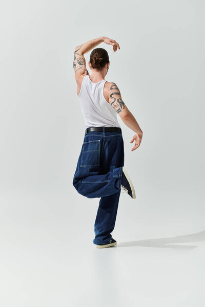 Красивый мужчина в белой рубашке и джинсах демонстрирует свои танцевальные навыки.