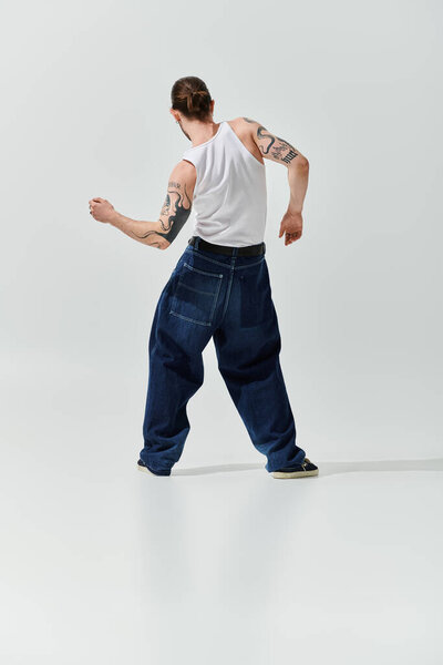 Стильный белый мужчина с татуировкой на руке в нетронутой белой обстановке.