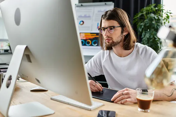 stock image A man focused at his desk, working diligently on a computer.