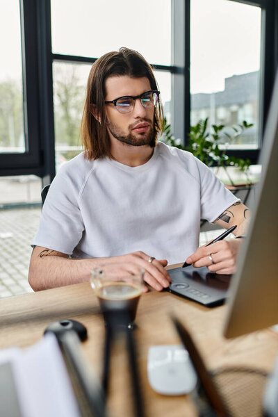 A focused man sits at a desk, utilizing a laptop for work.