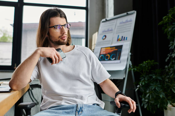 A caucasian businessman with long hair and glasses sitting in a chair.