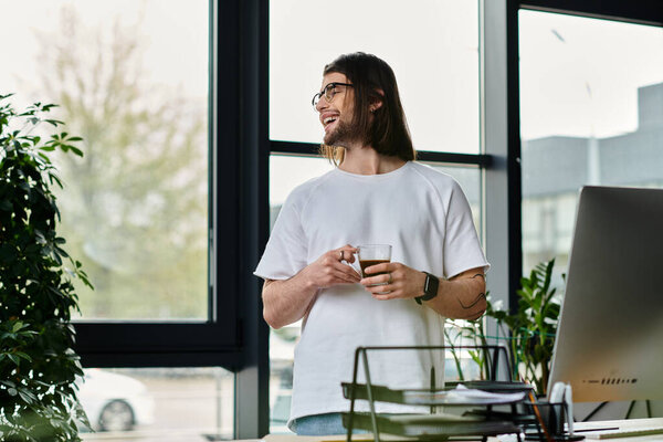 A handsome Caucasian businessman stands in front of a laptop computer, working from his office.