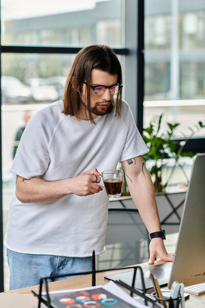 A focused Caucasian businessman working on a laptop while sipping coffee.