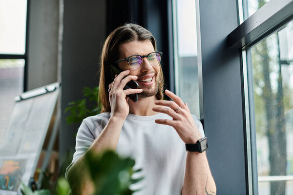 Handsome businessman talking on cell phone next to window.