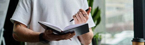 Handsome businessman pens thoughts in book.