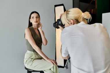 A woman gracefully sits on a stool in front of a photographer. clipart