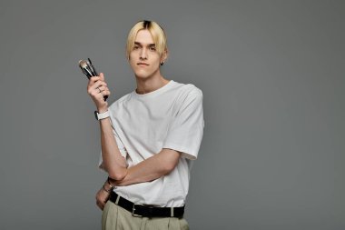 Makyaj fırçalarıyla dolu küçük bir çanta taşıyan şık bir adam..