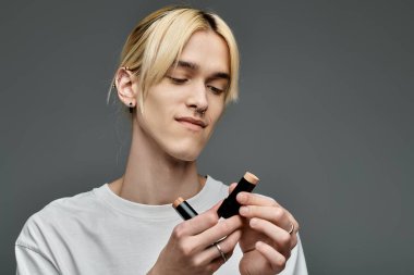 A man with blonde hair looks at makeup product. clipart