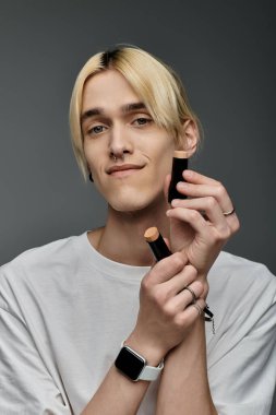 Şık bir adam kendine güvenen bir makyaj malzemesini elinde tutar..