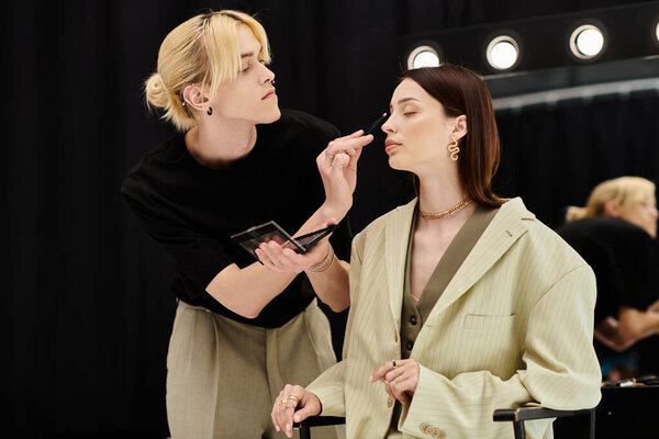 A makeup artist applies eyeshadows to a womans face.