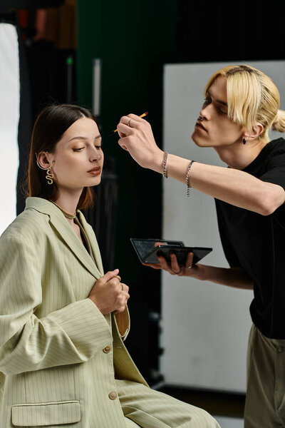 A makeup artist applies makeup to a female clients face.