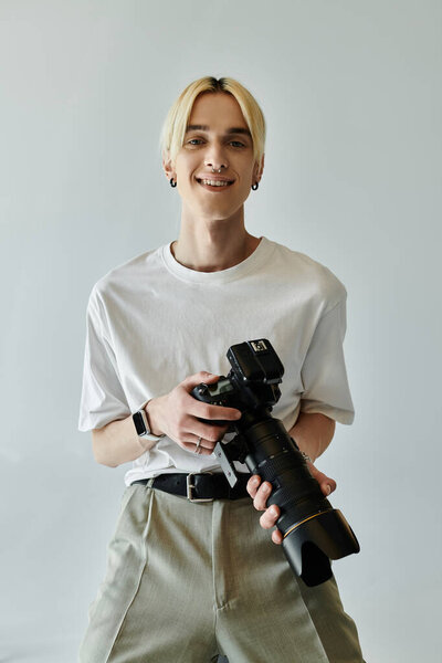 Young man smiles while holding camera.