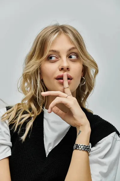 stock image A stylish young woman with blonde hair presses her finger to her lips, signaling for silence.