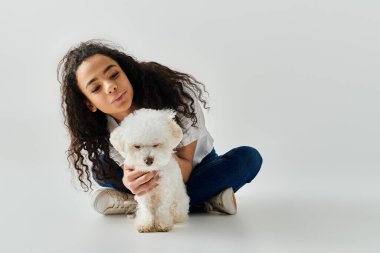 Bir kadın küçük beyaz Bichon Frise köpeğini sevgiyle kucaklıyor..