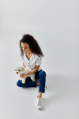 Beyaz Bichon Frise 'iyle yerde oturan kadın..