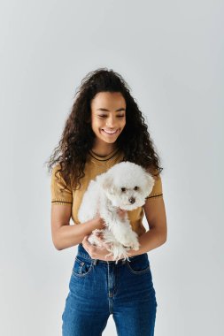 Young woman lovingly cradles her bichon frise in her hands. clipart