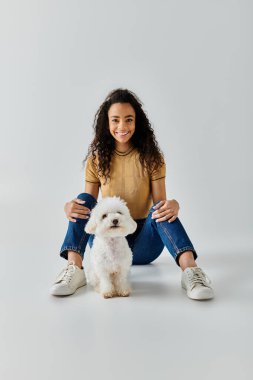 Beyaz köpeğiyle oturan genç bir kadın..