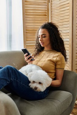 Kanepede oturan bir kadın, elinde beyaz bir köpek.