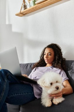 Dizüstü bilgisayarlı ve bichon köpekli bir kadın..