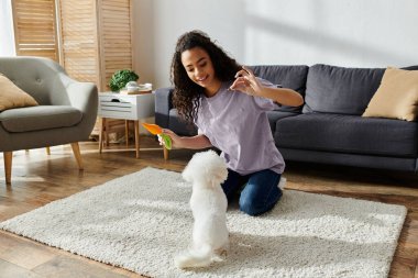 Diz çökmüş bir kadın, yerde Bichon Frise köpeğiyle bağ kuruyor..