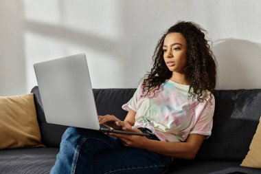 Kanepede oturan bir kadın laptopuyla birden fazla iş yapıyor..