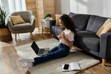 Evde dizüstü bilgisayarlı bir kadın oturuyor..