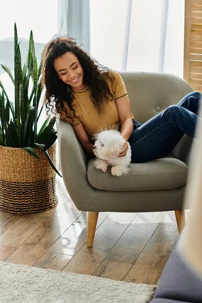 Genç bir kadın oturmuş, kollarında beyaz bir köpek besliyordu..