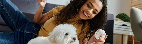 stock image A woman sitting on a couch, tenderly holding her bichon frise dog.