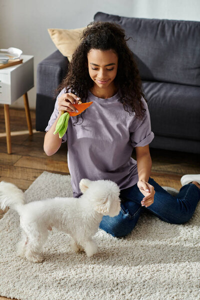 Woman sitting, bonding with white bichon frise dog on floor.