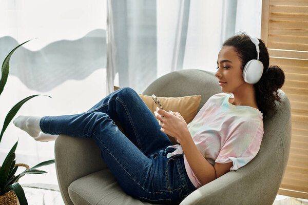 A woman in a chair, immersed in music with headphones on.